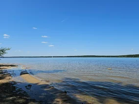 Miniatura: Zalew otoczony lasami i piaszczystą plażą....