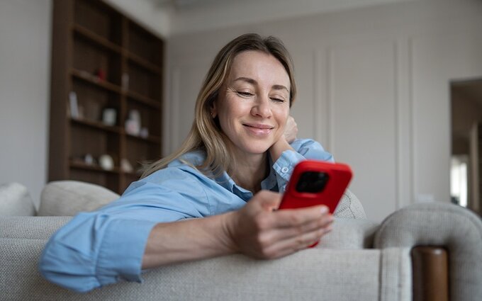 Kobieta korzystająca z smartphona na kanapie w salonie