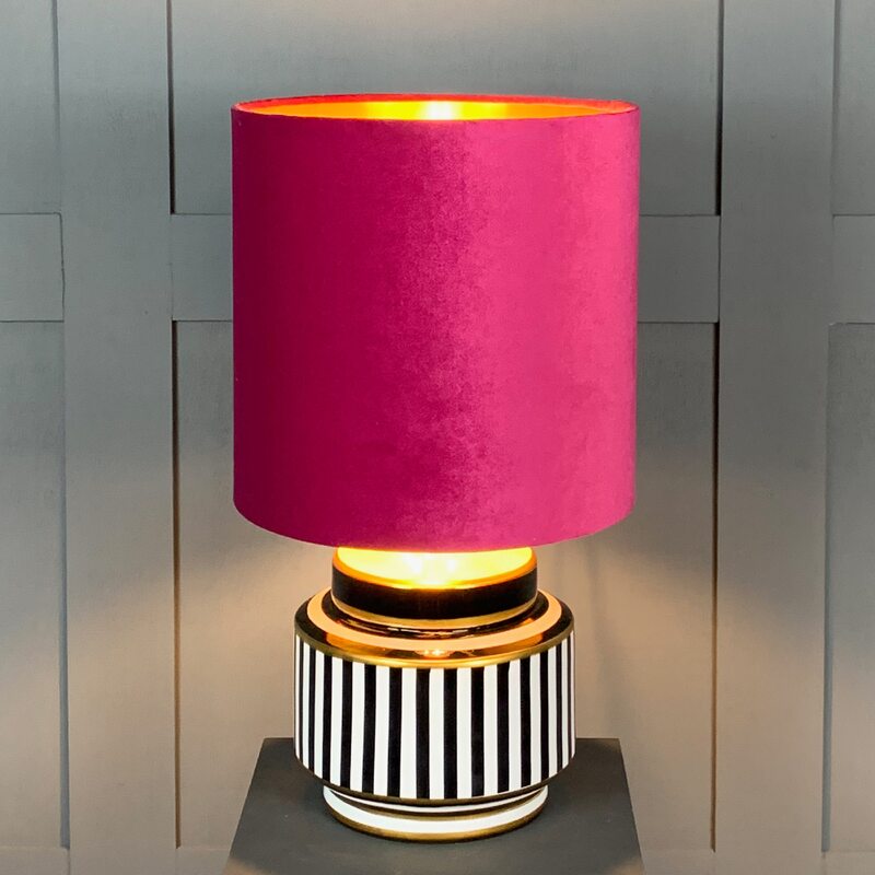 Lampa z różowym kloszem i czarno-białą podstawą nawiązująca do stylu proponowanego przez Grupę Memphis na początku lat 80. XX wieku