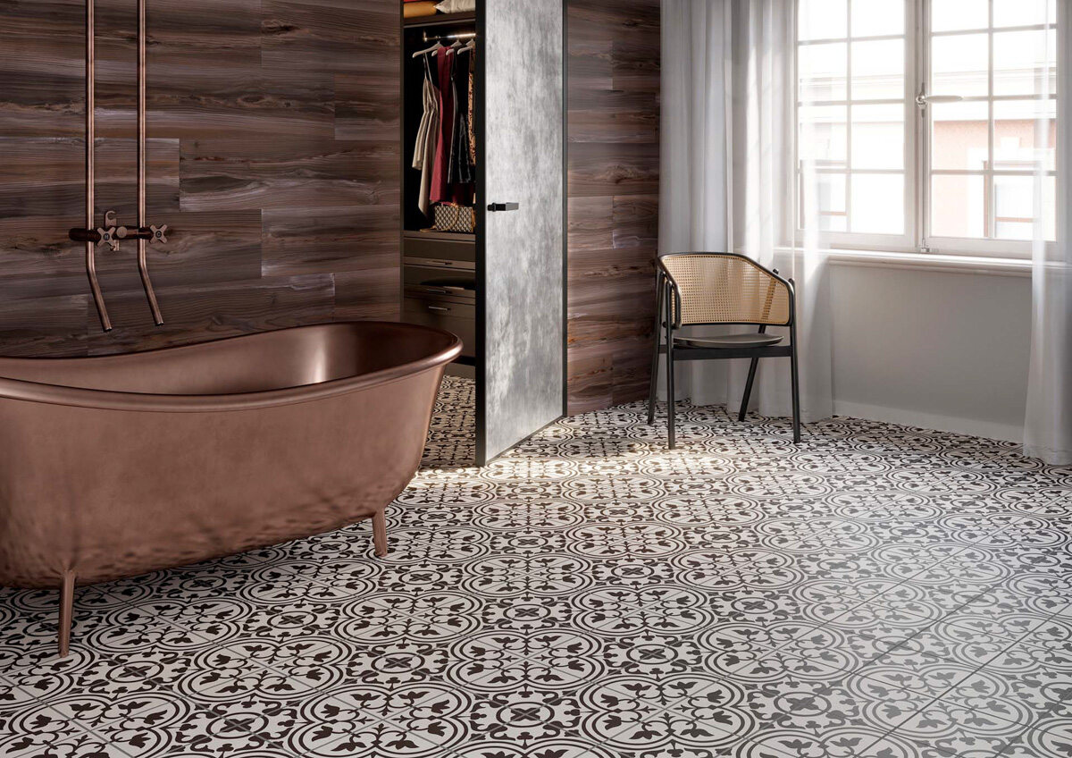 Stylizowane płytki marki Apavisa przypominają hiszpańskie azulejos. Podłoga we wzory jest idealnym tłem dla miedzianej wanny. Całości aranżacji dopełnia miedziana armatura. To propozycja do łazienki w stylu loftowym 