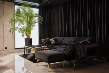 Lejąca się kotara, która kojarzy się z kurtyną i aksamitna sofa tworzą w salonie nieco teatralną atmosferę 