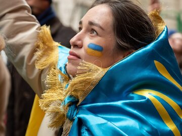 Kobieta owinięta w ukraińską flagę na demonstracji