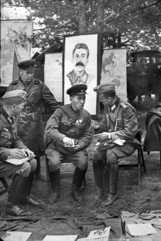 Oficerowie radzieccy i niemieccy dyskutują przed paradą w Brześciu w 1939 roku. Za nimi stoi portret Stalina. 