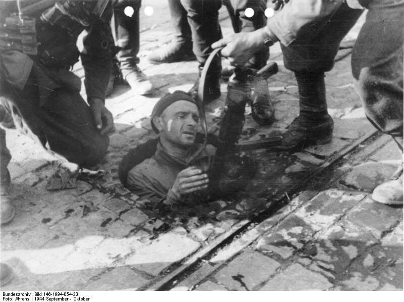 Powstaniec wychodzi z kanału na terenie zajętym przez Niemców 