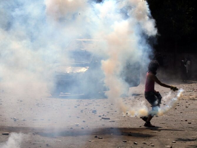 Uczestnik protestów w Kairze odrzuca granat gazowy (fot. PAP/EPA/KHALED ELFIQI)