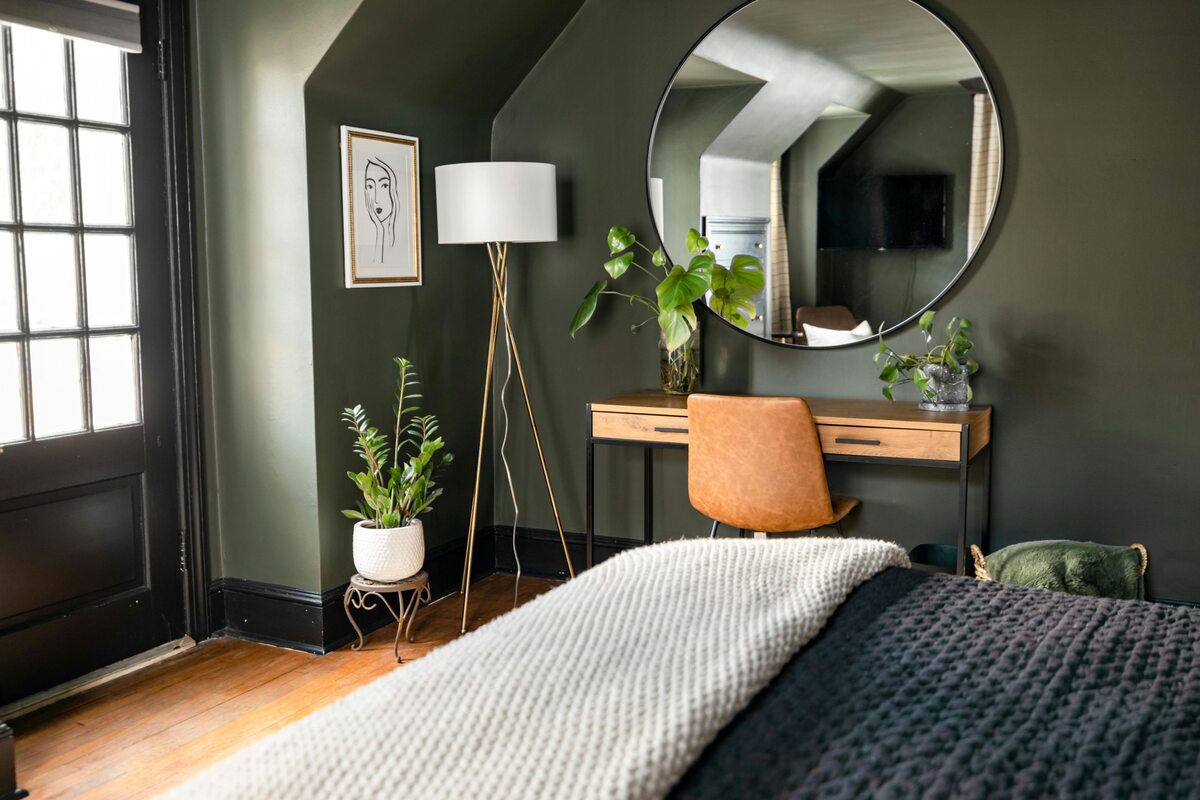 Sypialnia w modnym, przydymionym zielonym kolorze. W paletach barw producentów farb taki odcień występuje często jako „forest green” 