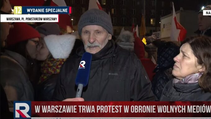 Całujące się kobiety na relacji z protestu w TV Republika. Zostały zasłonięte flagą