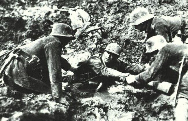 3 niemieckich żołnierzy pomaga Francuzowi, który utknął w mule na polu bitwy pod Verdun (I WŚ, 1916)