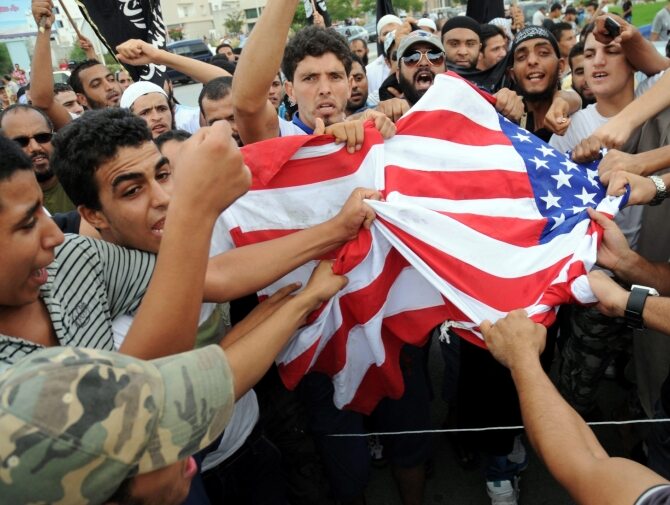 Demonstraci w Tunisie rozrywają amerykańską flagę (fot. PAP/EPA/STR)