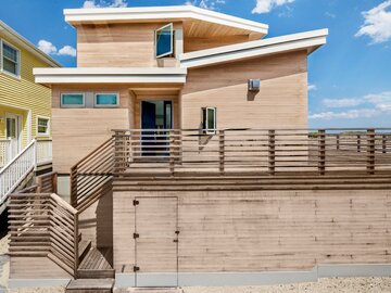 Drewniany dom na&nbsp;plaży, drzwiczki pod&nbsp;tarasem prowadzą bezpośrednio pod&nbsp;prysznic, projekt BFDO Architects