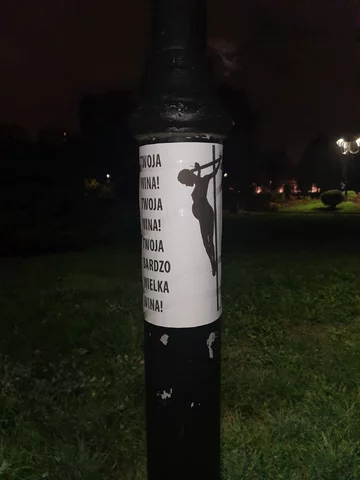 Plakat na latarni koło kościoła 