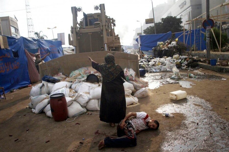 Kobieta zatrzymuje buldożer przed rannym protestującym (Egipt, 2013)