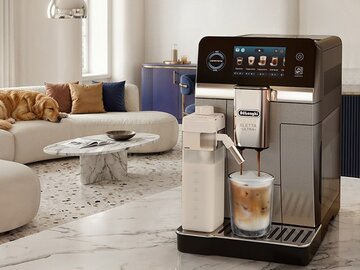Nowoczesny ekspres De&rsquo;Longhi Eletta Ultra na&nbsp;stoliku w&nbsp;salonie z&nbsp;filiżanką kawy i&nbsp;śpiącym psem na&nbsp;kanapie w&nbsp;tle