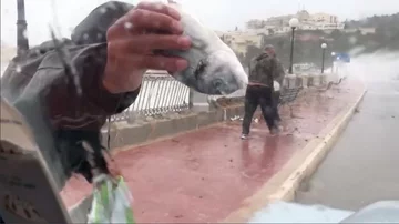 Mieszkaniec chwali się znalezioną rybą 