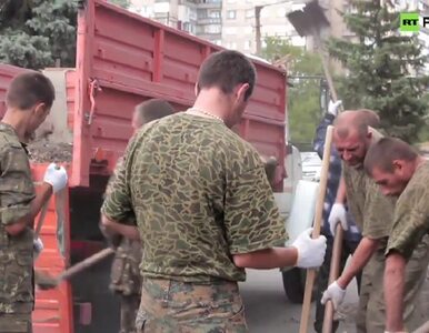 Ukraińscy żołnierze w niewoli pod lufą karabinów sprzątają ulice