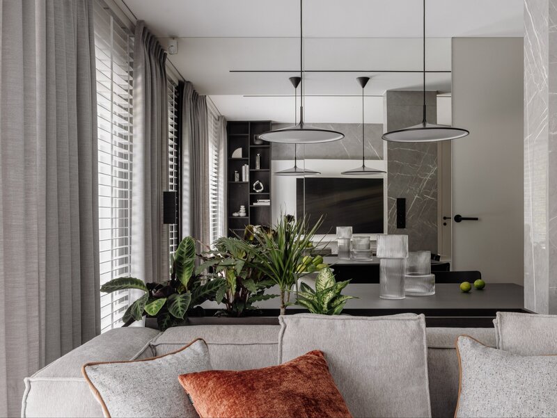Salon i&nbsp;kuchnia w&nbsp;jednej, sp&oacute;jnej stylistyce &ndash; ciemne drewno, kamień i&nbsp;subtelne oświetlenie podkreślają nowoczesny, apartamentowy charakter wnętrza