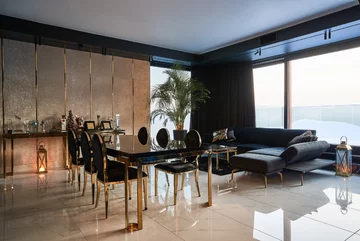 Elegancki stół postawiono pomiędzy aneksem kuchennym a sofą. Cleo wybrała współczesną wariację na temat klasycznych „Ludwików” z oparciem w kształcie medalionów i wdzięcznie wygiętą nóżką 