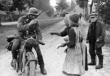 Niemiecki żołnierz na motocyklu jest częstowany piciem przez starsze kobiety „Volksdeutsche wręczyli swoim wyzwolicielom świeży napój” – głosi niemiecka propaganda