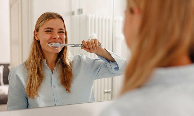 Kobieta myjąca zęby w&nbsp;łazience