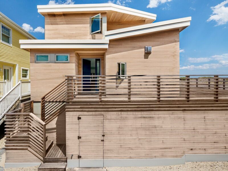 Drewniany dom na plaży, drzwiczki pod tarasem prowadzą bezpośrednio pod prysznic, projekt BFDO Architects
