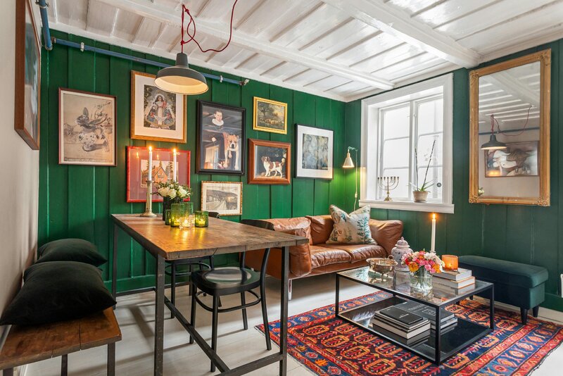Zielona boazeria, galeria obraz&oacute;w i&nbsp;ciepłe światło &ndash; przykład, jak jeden odważny kolor potrafi całkowicie odmienić salon bez efektu przesady