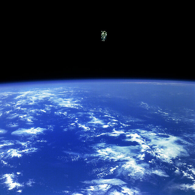 Astronauta Bruce McCandless w przestrzeni kosmicznej - najodleglejszy spacer kosmiczny, jaki kieykolwiek przeprowadzono. Możliwe było to dzięki specjalnemu plecakowi z małymi dyszami napędzanymi azotem.  McCandless znajduje się 320 stóp (ok. 100 metrów) o