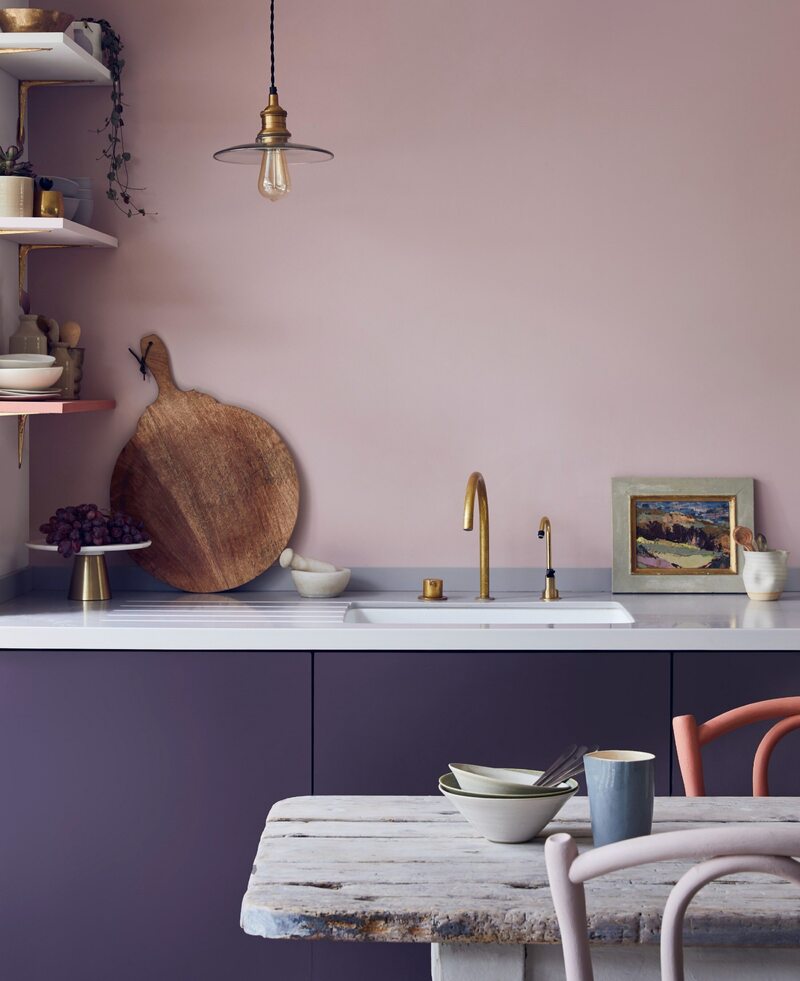 Kuchnia z różową ścianą i fioletowymi szafkami