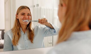 Kobieta myjąca zęby w&nbsp;łazience