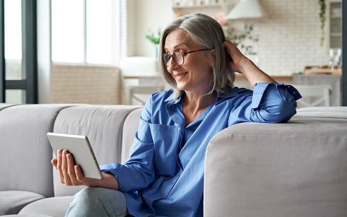 Starsza kobieta oglądająca wideo na tablecie w salonie