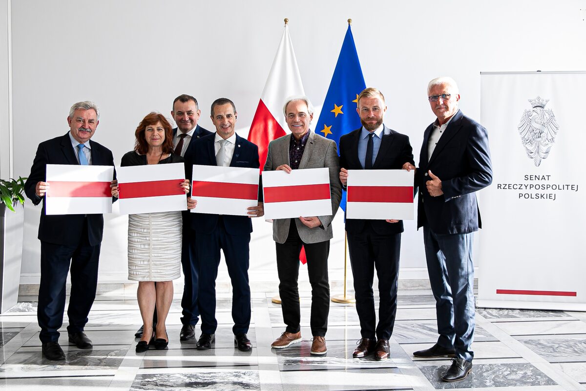 Senatorowie trzymający biało-czerwono-białe barwy Białorusi 