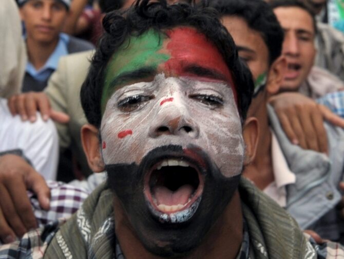 Uczestnik demonstracji w Jemenie z twarzą wymalowaną w barwy syryjskiej rewolucji (fot. PAP/EPA/MOHAMMED HAMOUD)