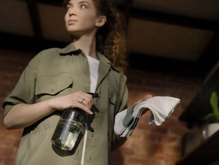 Woman in Green Button Up Shirt Holding Clear Glass Bottle