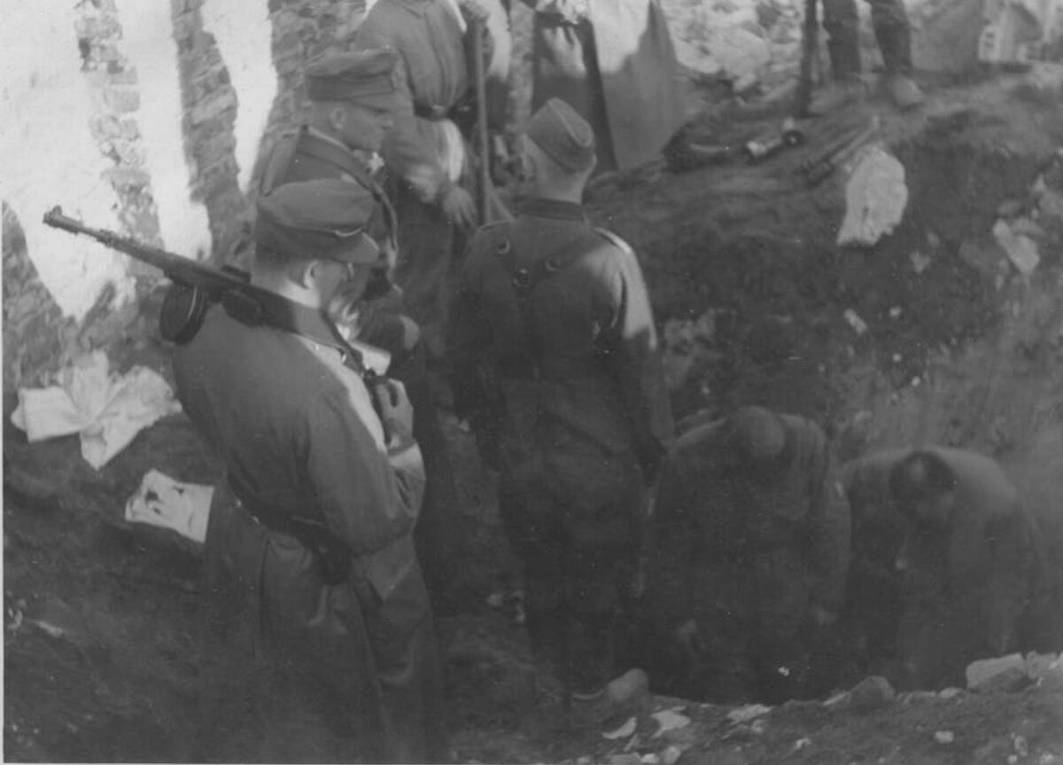 Odkopywanie bunkra. Niemiecki podpis pod zdjęciem: „Otwarcie bunkra” Żołnierze SS zmuszają Żydów do odkopania wejścia do bunkra.