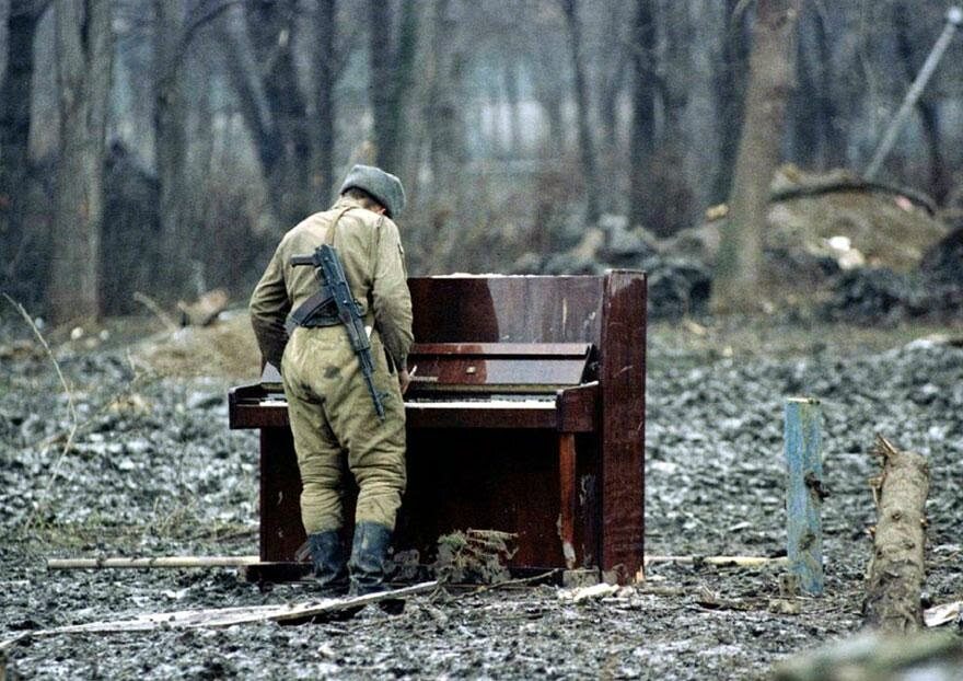Rosyjski żołnierz gra na porzuconym pianinie w Czeczenii w 1994 r. (fot. epicdash.com)