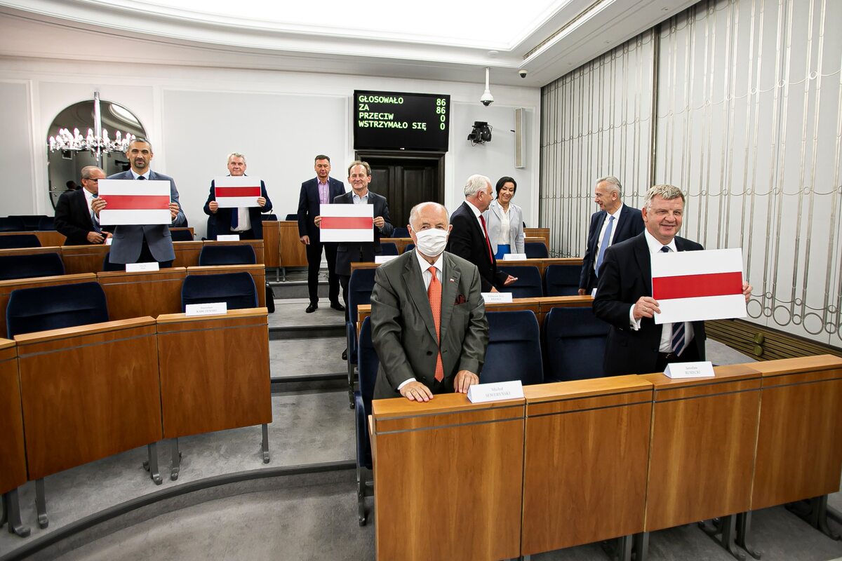Senatorowie trzymający biało-czerwono-białe barwy Białorusi 