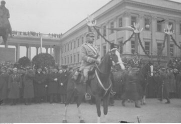 Piłsudski na&nbsp;Kasztance przyjmuje defiladę. W&nbsp;tle widoczny Pałac Saski i&nbsp;pomnik księcia J&oacute;zefa Poniatowskiego