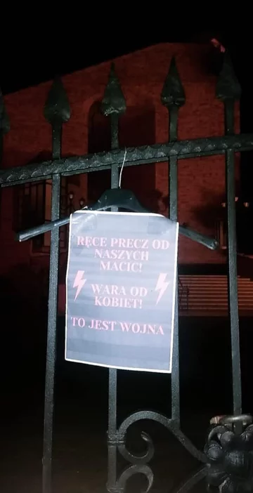 Wieszak i plakat na ogrodzeniu kościoła 