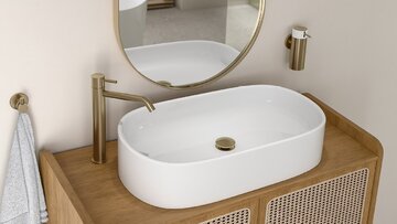 Oszczędne, eleganckie formy &ndash; owalna misa nablatowej umywalki, szafka z&nbsp;rattanowym wyplotem oraz&nbsp;bateria Ciriculus w&nbsp;odcieniu szczotkowanego złota. Do&nbsp;tego akcesoriami z&nbsp;linii Smile w&nbsp;tym samym wykończeniu