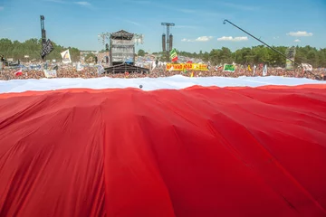 Olbrzymia biało-czerwona flaga nad woodstockowym polem rozciągnięta podczas otwarcia festiwalu, fot. PAP Lech Muszyński