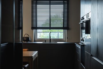 Projekt pracowni masz.design pokazuje, że ciemna kolorystyka, naturalne drewno i światło mogą stworzyć wnętrze pełne spokoju, elegancji i ponadczasowego charakteru 