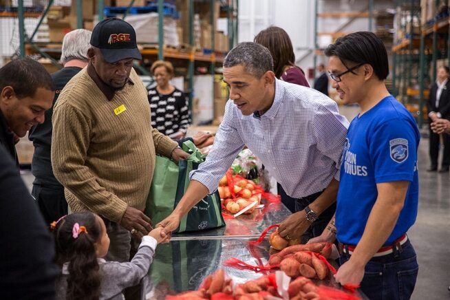 Obama wita się z małą dziewczynką w trakcie pełnienia funkcji wolontariusza w Capital Area Food Bank w Waszyngtonie.