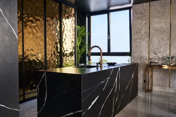 W apartamencie wszystko jest ze sobą perfekcyjnie skomponowane. Złoto pokrywa duże płaszczyzny, meble i akcesoria, np. armaturę kuchenną i łazienkową 