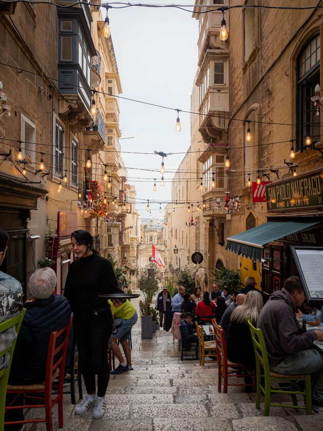 Uliczka w Valletcie Ponieważ na Malcie ciepło jest w zasadzie przez cały rok, mieszkańcy chętnie spożywają posiłki na zewnątrz. Między kamienicami w Valletcie często rozciągane jest klimatyczne oświetlenie, a ponieważ miejsca na restauracyjne ogródki jest tam niewiele, stoliki są wystawiane na chodnikach, którymi spacerują turyści.