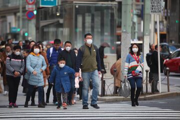 Azjatyccy turyści w maskach na twarzy odwiedzają dzielnicę handlową Ginza w Tokio