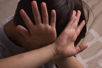 Chłopiec zasłaniający się dłońmi, zdjęcie ilustracyjne