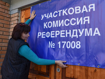 Członek komisji wyborczej w Doniecku wywieszająca transparent o referendum