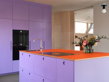 Inspirujące wnętrze z fioletowo-pomarańczową zabudową kuchenną