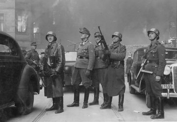 Jürgen Stroop pozuje na tle płonącego getta. Niemiecki podpis pod zdjęciem: „Dowódca wielkiej operacji”
