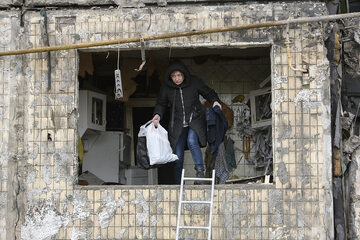 Kijów, kobieta wynosi swoje rzeczy ze zbombardowanego bloku