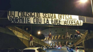Kukły piłkarzy i transparent przed Koloseum